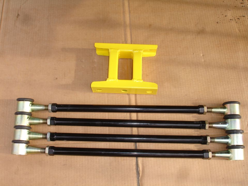 Four black adjustable control arms and a yellow suspension component laid out on a cardboard surface