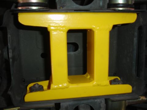 1995 Ford Taurus - Close-up view of a yellow H-brace part attached to a vehicle's undercarriage.