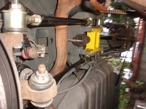1995 Ford Taurus - Close-up view of aftermarket rear suspension components, including a yellow brace and black adjustable arms.