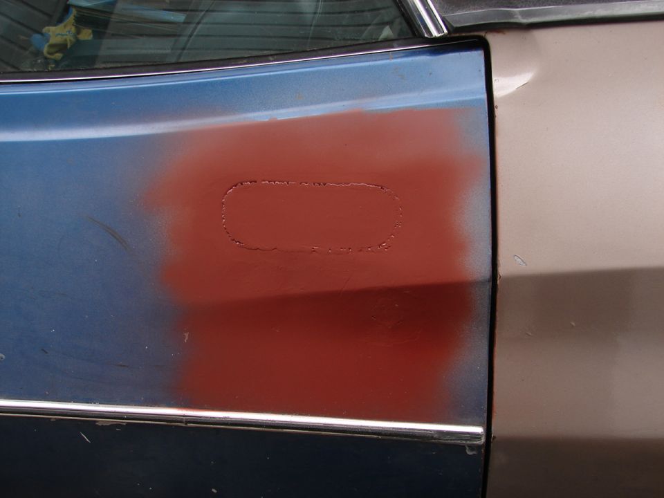 Blue car door with red primer patch and chrome trim