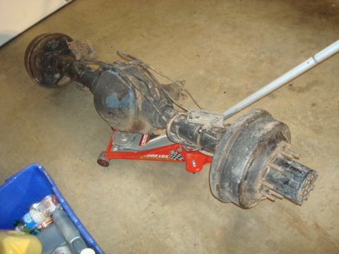 1995 Ford Bronco - Rear axle assembly, likely from a truck or SUV, is supported by a red hydraulic jack.