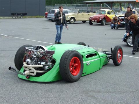 1968 Ford Mustang - Customized Volkswagen Beetle hot rod with exposed engine and red wheels at an outdoor event.