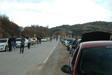2006 Cadillac STS - A gathering of vehicles and people on the side of a road with hills in the background.