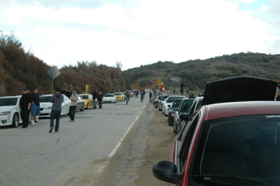 Cars and spectators lining a canyon road at a hillside car gathering