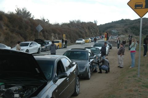 2006 Cadillac STS - A gathering of cars on a roadside, with several vehicles lined up and people observing them.