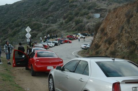 2006 Cadillac STS - A silver sedan is parked on a dirt road with other vehicles and people gathered on a hillside.