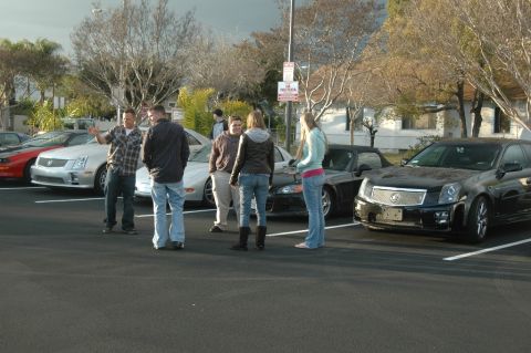 2006 Cadillac STS - A group of people stand around several cars, including a black Cadillac STS.