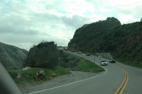 2006 Cadillac STS - A convoy of vehicles navigates a scenic, winding mountain road.