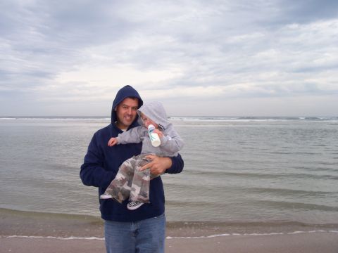 1994 Ford Bronco - A man and a baby enjoy a day at the beach under a cloudy sky.