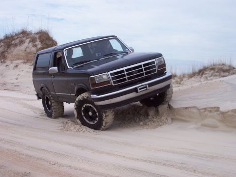 1994 Ford Bronco - This 1994 Ford Bronco navigates a sandy terrain, with its tires kicking up sand.