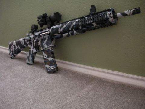 1996 Ford Bronco - An assault rifle with a distinctive camouflage paint job rests against a wall.