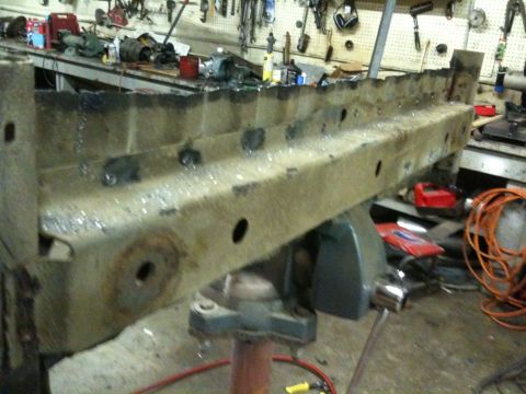 1993 Ford Bronco - A heavily rusted metal frame part is clamped in a vise, with tools and equipment in the background.