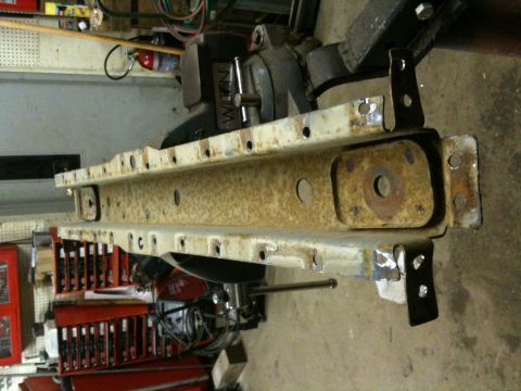 1993 Ford Bronco - A heavily rusted metal frame component, likely a chassis part, is shown in a workshop setting.