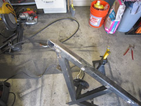 1996 Ford Bronco - A metal frame is supported by jack stands in a workshop setting, with various tools visible in the background.