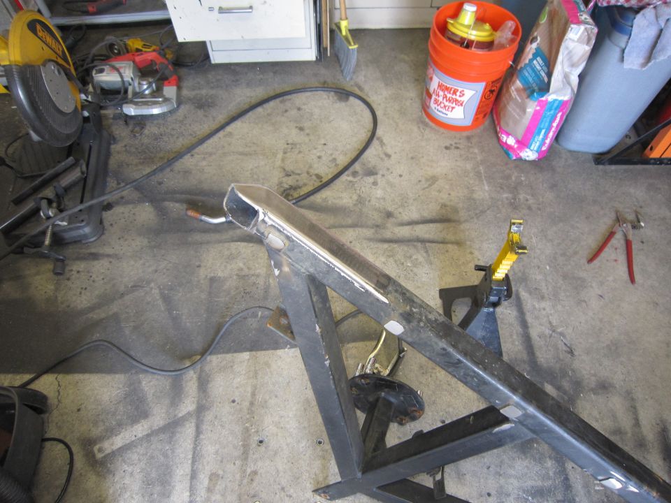 Metal frame on jack stands in a garage with tools nearby