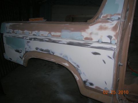 1985 Ford Bronco - Rear quarter panel of a Ford Bronco undergoing bodywork, showing filler and primer application.