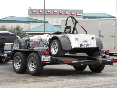 2003 Mazda Protege - An open-top race car with Hoosier branding is transported on a trailer, with Texas flags flying in the background.