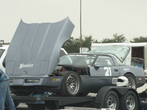 2003 Mazda Protege - A gray Chevrolet Corvette C4 race car is loaded onto a trailer with its hood open.