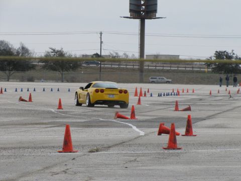 2003 Mazda Protege - A yellow sports car navigates a course marked by orange cones on a cloudy day.