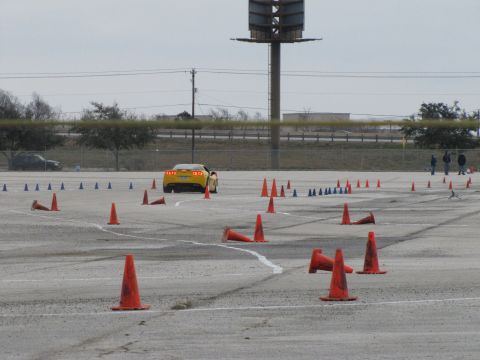 2003 Mazda Protege - A yellow sports car navigates a course marked by traffic cones on a cloudy day.