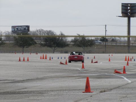 2003 Mazda Protege - A red convertible is seen from the rear, driving through a course marked by traffic cones.