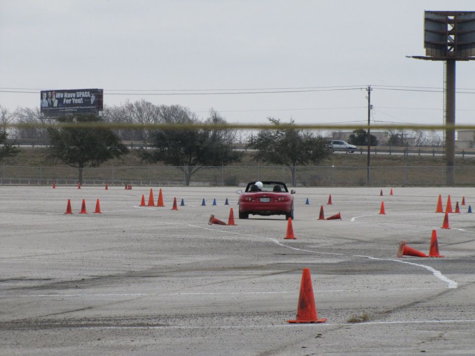 Red convertible sports car navigating a cone course