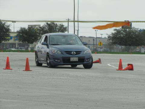 2003 Mazda Protege - A blue hatchback navigates a course marked by orange cones on a cloudy day.