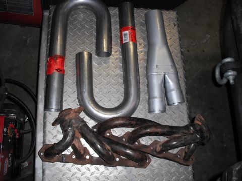 1991 Ford Bronco - Exhaust manifold and Y-pipe components are displayed on a metal surface, with red labels visible on some pipes.