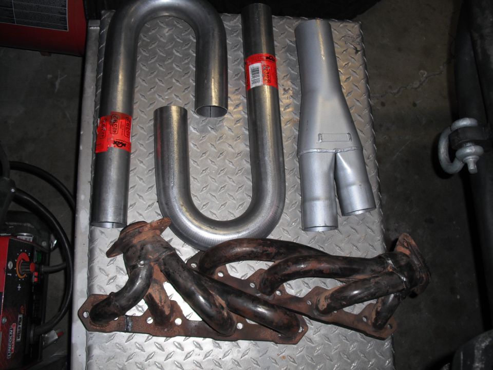 Exhaust manifold and Y-pipe components laid out on a diamond plate surface