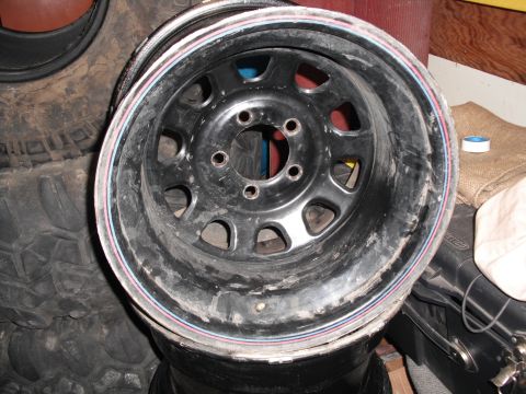 1991 Ford Bronco - A single worn steel wheel rim is shown, stacked with other tires.