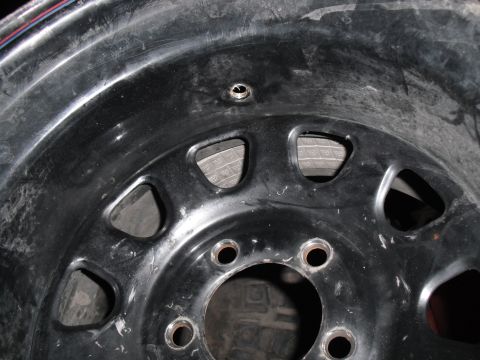 1991 Ford Bronco - Close-up of a black steel wheel rim, showing its construction and bolt holes.