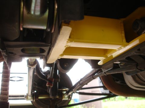 1995 Ford Taurus - Close-up view of a yellow aftermarket chassis brace mounted beneath a vehicle.