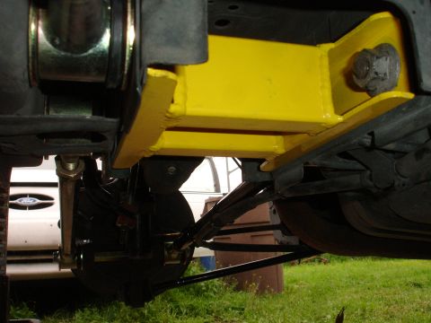 1995 Ford Taurus - Close-up of a yellow aftermarket chassis brace installed on a vehicle's undercarriage.