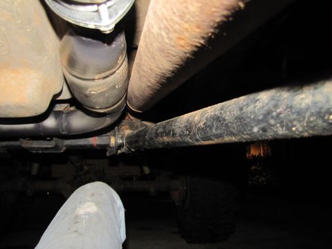 1995 Ford Bronco - Close-up view of the undercarriage, focusing on the exhaust system and driveshaft components.
