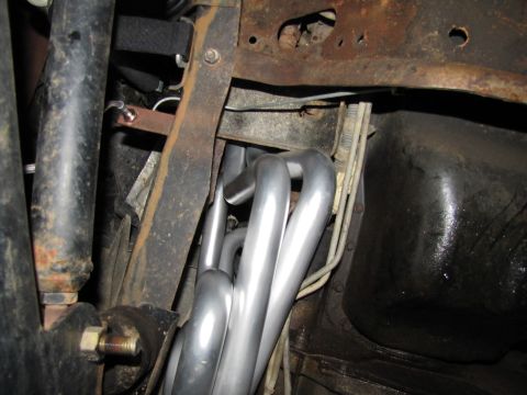 1995 Ford Bronco - Close-up view of exhaust pipes and undercarriage of a vehicle, showing rust and mechanical parts.