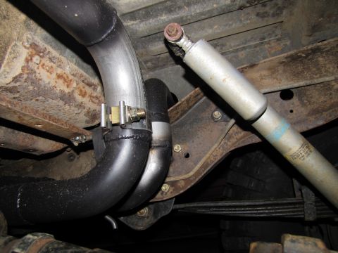 1995 Ford Bronco - Close-up view of the undercarriage, focusing on the exhaust system and a rear shock absorber.