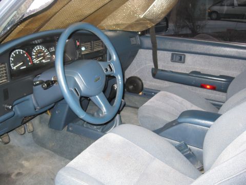 1990 Toyota Pickup/SR5 - The interior of a Toyota truck shows a blue dashboard and steering wheel, with cloth seats visible.
