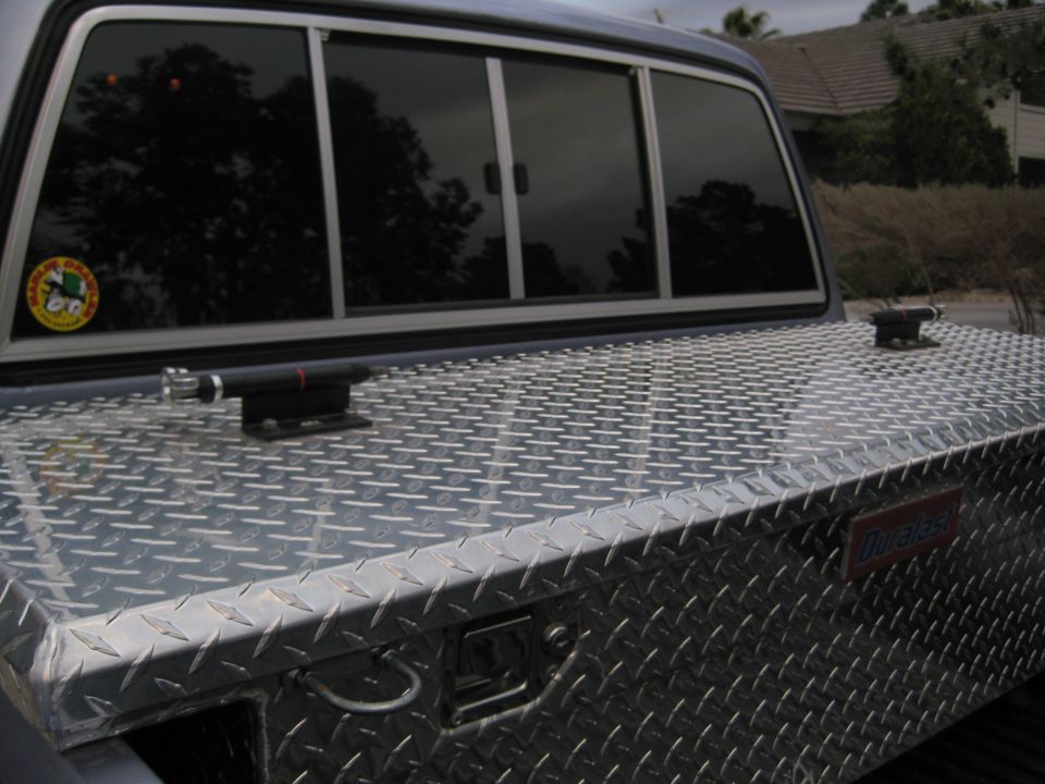 Diamond plate aluminum crossbed toolbox in pickup bed ahead of sliding rear window