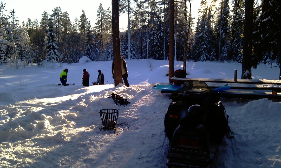 Snowmobile and people in a snowy clearing at sunset