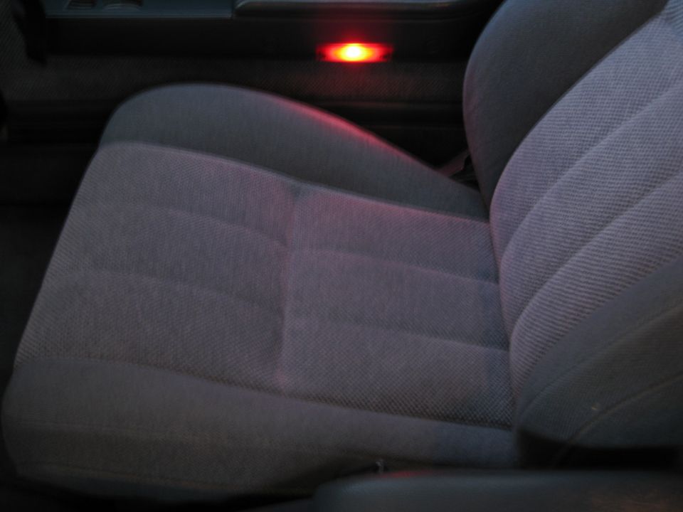 Gray cloth bucket seat in a dim truck interior with a red courtesy light behind
