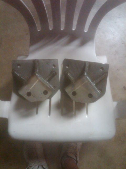1982 Ford Bronco - Two metal brackets are placed on a white plastic chair, possibly for sale or storage.