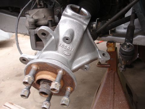 1995 Ford Taurus - A vehicle's front suspension spindle and brake caliper are shown, with the wheel removed and the vehicle supported by a jack stand.
