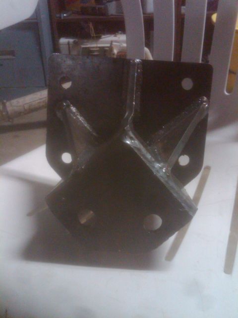 1982 Ford Bronco - A dark metal bracket with visible bolt holes and reinforcing supports is shown in close-up.