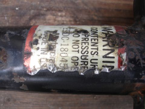 1995 Ford Taurus - Close-up of a shock absorber part showing a warning label with pressure information and manufacturing details.