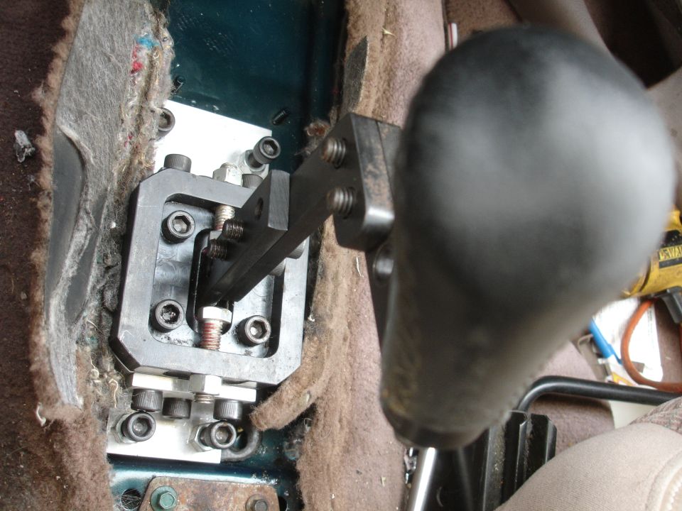 Short shifter mechanism installed in car interior, with black shift knob and exposed carpet