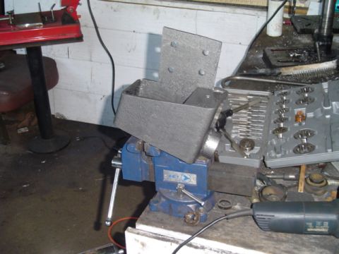 1993 Ford Bronco - A metal part is secured in a vise, surrounded by tools and workshop equipment.