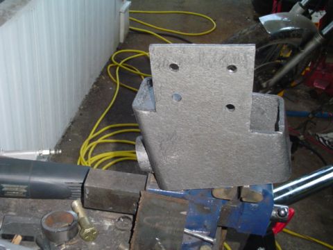 1993 Ford Bronco - A metal bracket is secured in a vise, with tools and a yellow cord in the background.