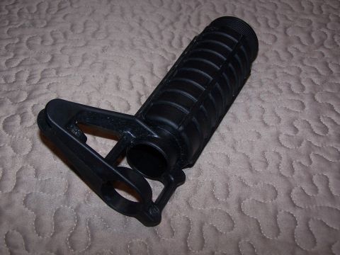 1986 Ford Bronco - A black plastic part, possibly a filter housing or connector, is shown on a textured surface.