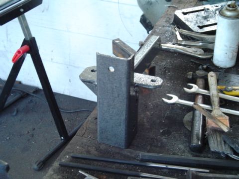 1993 Ford Bronco - A metal bracket is shown on a workbench with various tools and a spray can nearby.