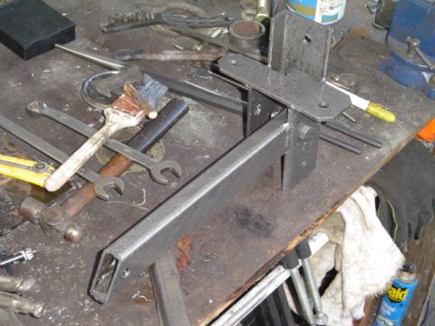 1993 Ford Bronco - Metal bracket assembly on a workbench with tools, likely for a vehicle repair or modification.